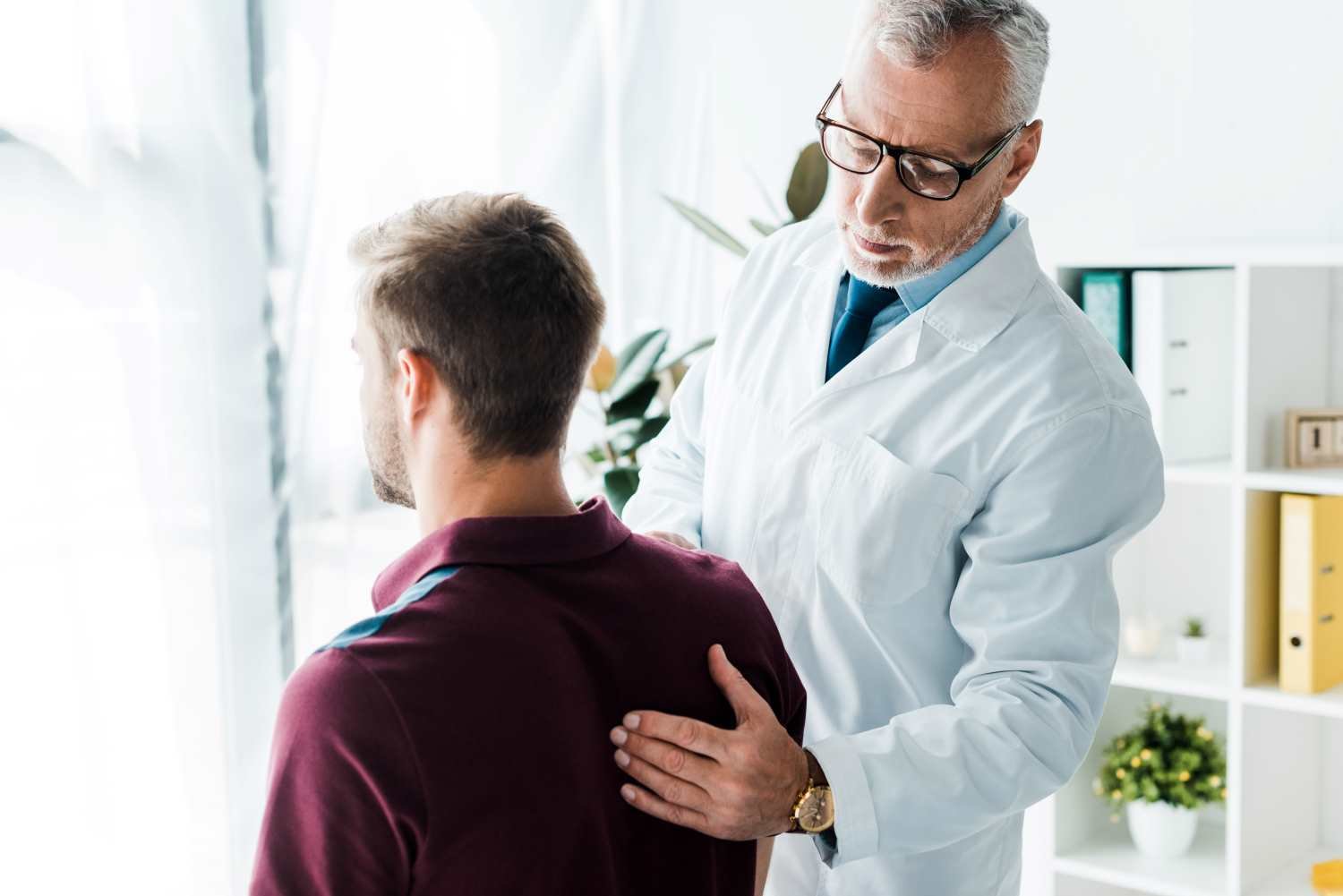 doctor-glasses-white-coat-touching-back-man-clinic
